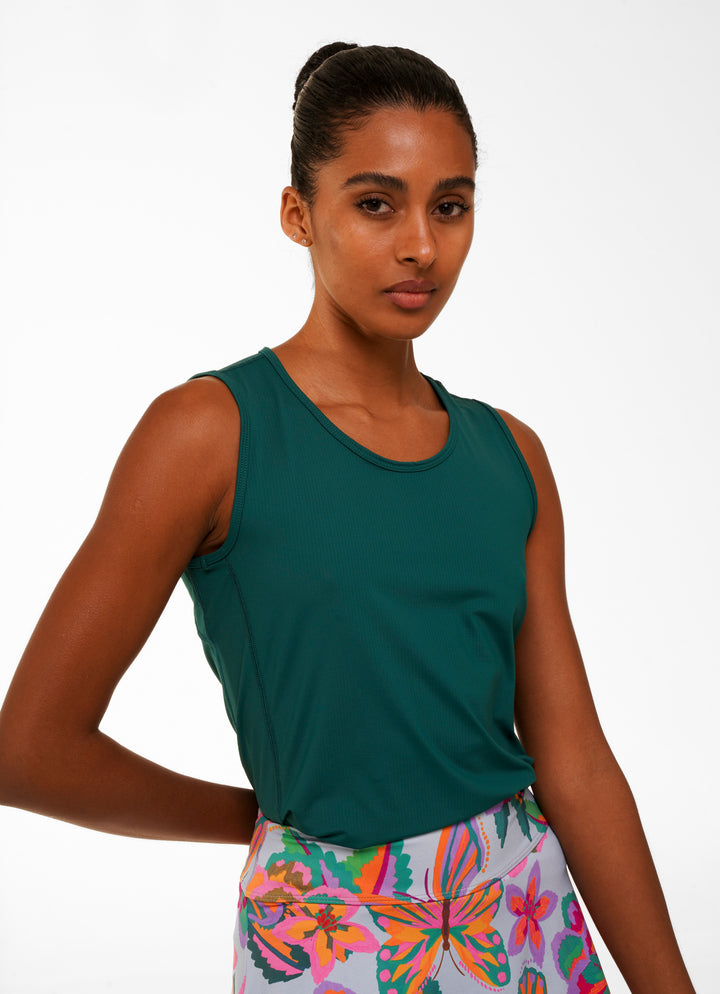 Woman wearing a green tank top and colorful floral shorts on a white background