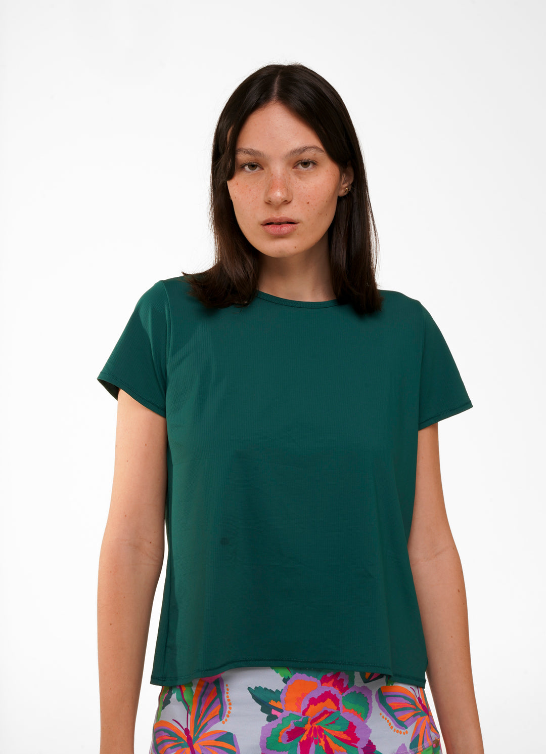 Woman wearing a green t-shirt with colorful pants on a white background