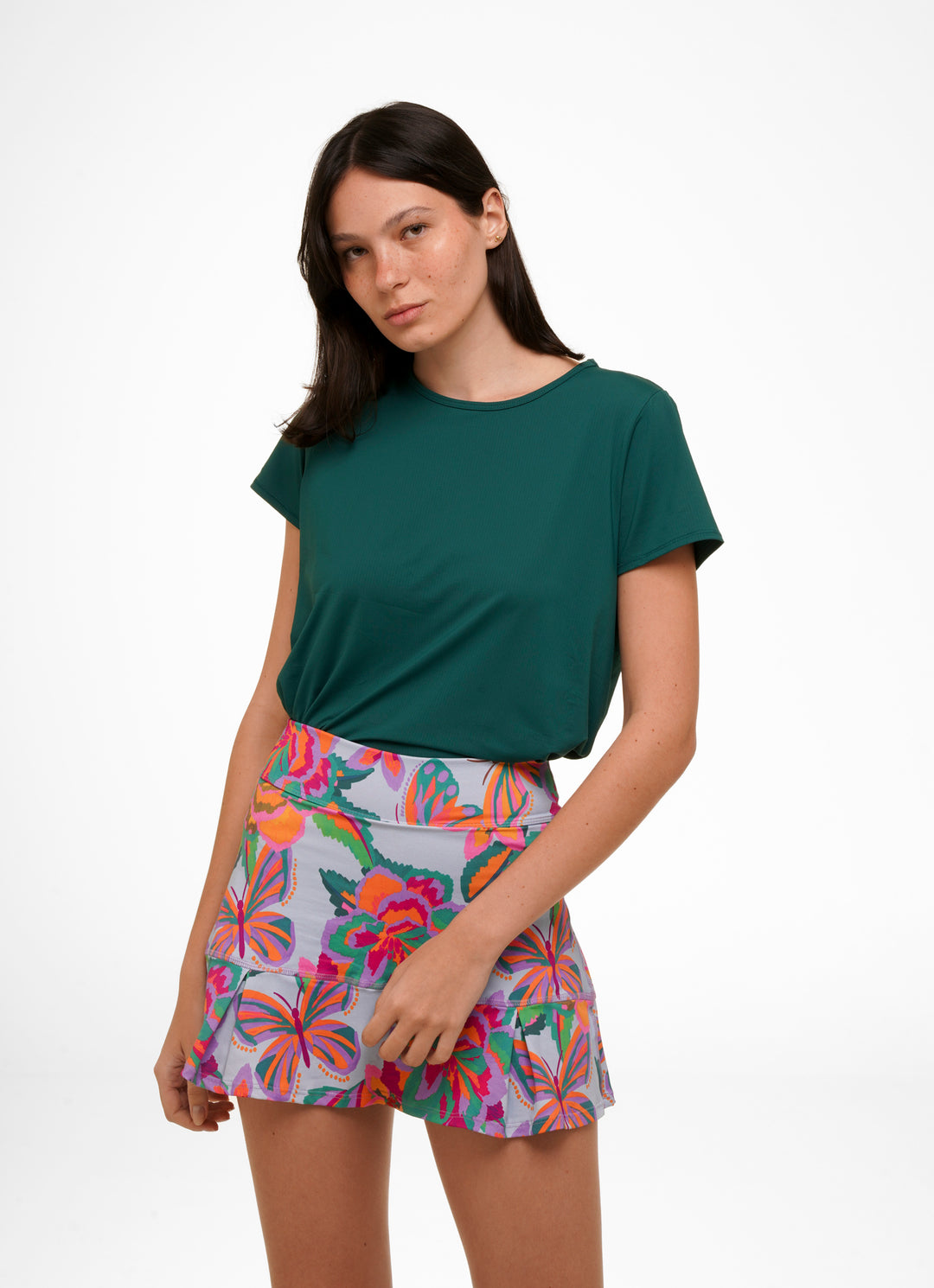 Woman wearing a green t-shirt and colorful floral skirt on a white background