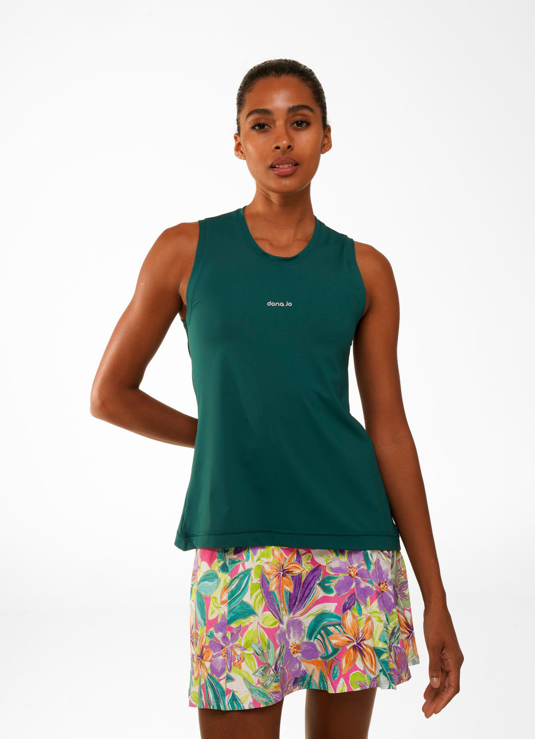 A female model wearing a green sleeveless tank top and a multicolored skirt with a floral pattern.