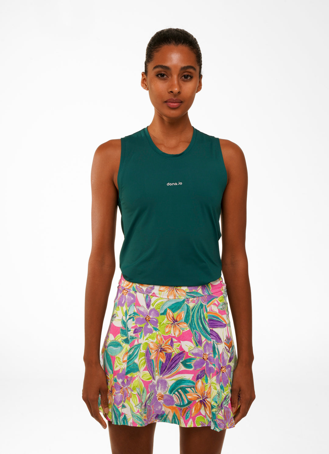 Woman wearing a green sleeveless top and colorful floral skirt on a white background