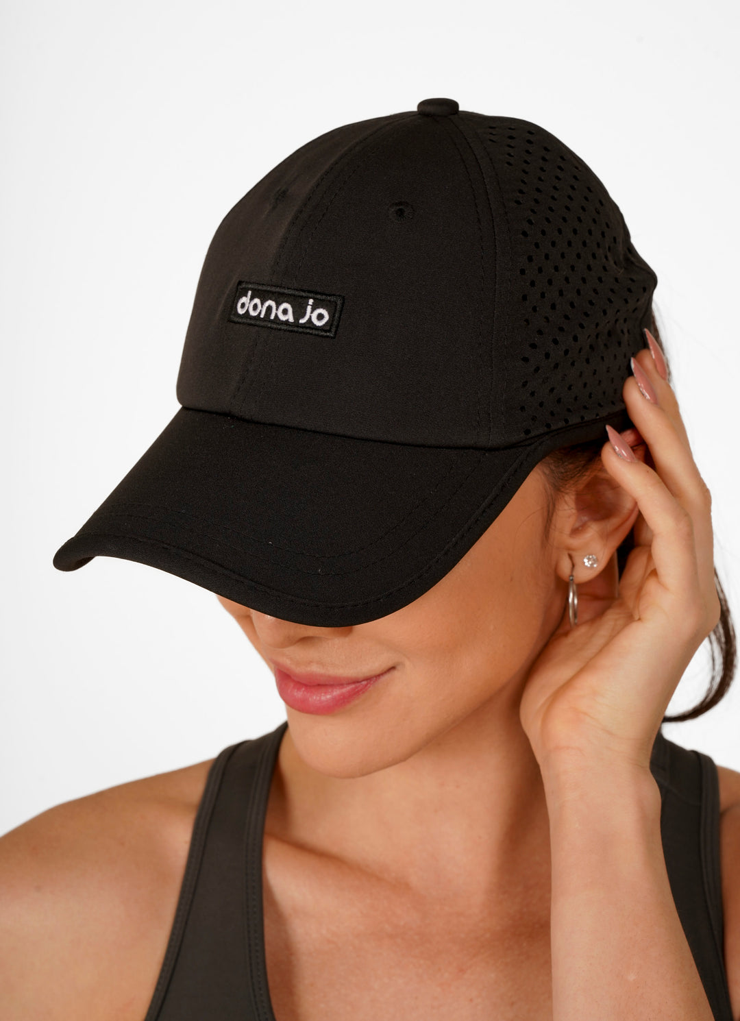 Woman wearing a black cap with 'dana jo' logo on a white background